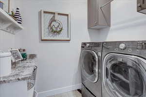 Laundry area with cabinets, light tile floors, and washing machine and clothes dryer