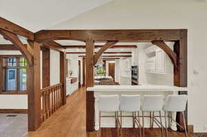 Kitchen with stainless steel double oven, white cabinetry, hardwood, and a kitchen bar