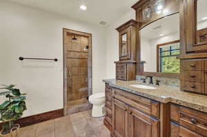 Bathroom with an enclosed shower, vanity, toilet, and tile floors