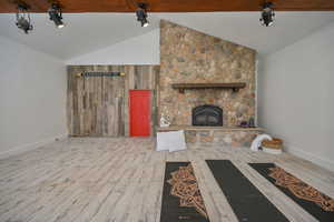 Barn featuring a stone fireplace, beam ceiling, and wood-look flooring