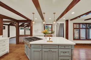 Kitchen with hardwood / wood floors, hanging light fixtures, white cabinetry, and a kitchen island