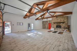 Barn featuring a stone fireplace, beam ceiling, and wood-look flooring