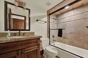 Full bathroom with toilet, tiled shower / bath combo, and large vanity