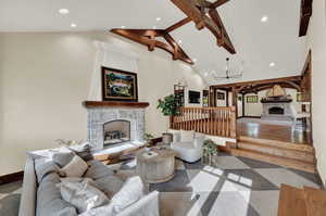 Tiled living room featuring high vaulted ceiling, beamed ceiling, a chandelier, and a fireplace