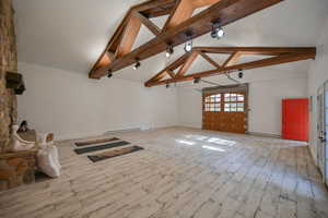 Barn featuring a stone fireplace, beam ceiling, and wood-look flooring