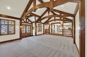 Empty room featuring french doors, carpet, and vaulted ceiling