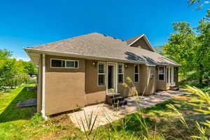 Rear view of property with a lawn and a patio.