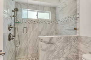 Primary bathroom with a rain head and marble tile enclosure.