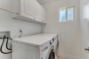 Laundry area featuring washer and dryer, cabinets, and drying rack.