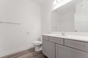 Bathroom with hardwood / wood-style flooring, vanity, toilet, and a shower