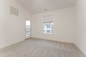 Carpeted empty room featuring vaulted ceiling