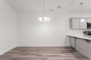 Unfurnished dining area featuring light hardwood / wood-style floors and a notable chandelier