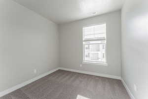 Carpeted empty room featuring a textured ceiling