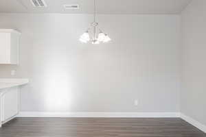 Unfurnished dining area featuring dark hardwood / wood-style flooring and an inviting chandelier