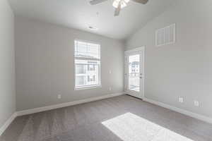 Carpeted empty room featuring a textured ceiling, ceiling fan, and lofted ceiling