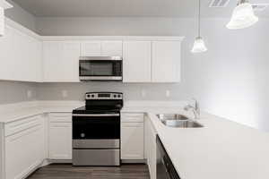 Kitchen featuring sink, white cabinets, pendant lighting, and appliances with stainless steel finishes