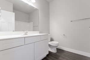 Bathroom featuring hardwood / wood-style flooring, vanity, toilet, and a shower