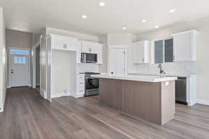 Kitchen with stainless steel appliances, tasteful backsplash, hardwood / wood-style floors, and a kitchen island