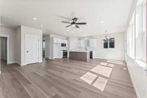 Unfurnished living room featuring light hardwood / wood-style floors and ceiling fan with notable chandelier