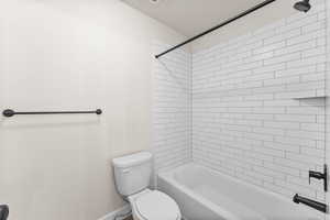 Bathroom featuring tiled shower / bath and toilet