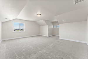 Additional living space with lofted ceiling and light colored carpet