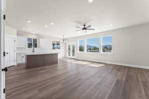 Interior space with ceiling fan with notable chandelier, sink, and dark hardwood / wood-style flooring