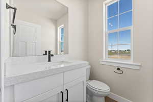 Bathroom with vanity with extensive cabinet space and toilet