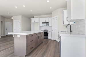 Kitchen with a center island, stainless steel gas range, hardwood / wood-style flooring, backsplash, and sink