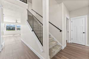 Stairway with wood-type flooring and ceiling fan