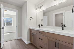 Bathroom with dual sinks, vanity with extensive cabinet space, and hardwood / wood-style flooring