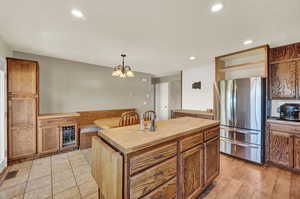 Kitchen with hanging light fixtures, a kitchen island, tile and laminate flooring, butcher block counters, and stainless steel refrigerator