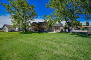 Back side of the home with the view of yard with a patio