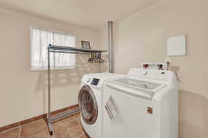 Clothes washing area featuring hookup for a washing machine, crown molding, independent washer and dryer, and light tile floors