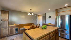 Kitchen with butcher block counters, stainless steel fridge, a kitchen island and light tile floors