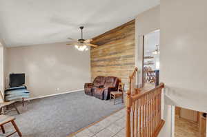 Sitting room featuring wooden walls, tile floors, ceiling fan and vaulted ceiling