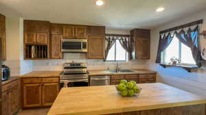 Kitchen featuring sink, stainless steel appliances, backsplash, and butcher block countertops.