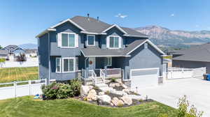 View of front of property featuring covered porch, a garage, a mountain view, and a front lawn