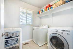 Laundry area featuring light tile patterned floors and independent washer and dryer