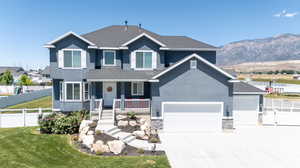 View of front of house featuring a garage, a front yard, a mountain view, and a porch