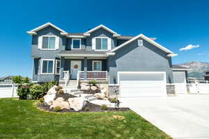 View of front of property with a front lawn, a garage, a mountain view, and a porch