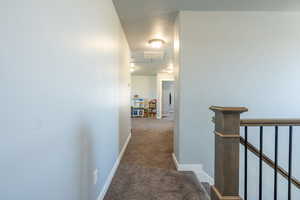 Hall featuring dark carpet and a textured ceiling