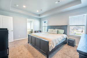 Bedroom featuring light colored carpet and a tray ceiling