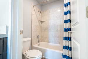 Bathroom with toilet and shower / bath combination with curtain