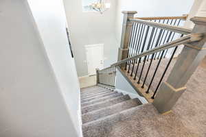 Stairway featuring carpet floors, an inviting chandelier, and a towering ceiling