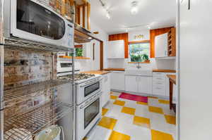 Kitchen featuring light tile flooring, tasteful backsplash, track lighting, sink, and white appliances