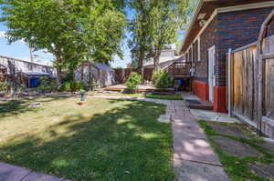 View of yard featuring a wooden deck and a storage shed