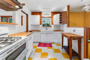 Kitchen with ceiling fan, white appliances, premium range hood, sink, and white cabinets