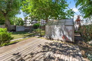 Wooden terrace featuring a lawn and a storage shed