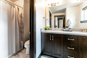 Full bathroom with tile flooring, vanity, toilet, and shower / tub combo with curtain