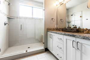 Bathroom featuring tile floors, an enclosed shower, and dual bowl vanity